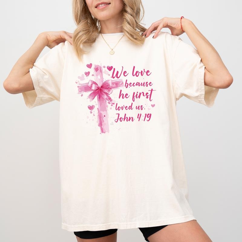 We Love Because He Loved Us First Comfort Colors Shirt, Bible Verse Graphic Tee, Coquette Cross Bow Unisex Tees, Valentine's Day Christian T-shirt